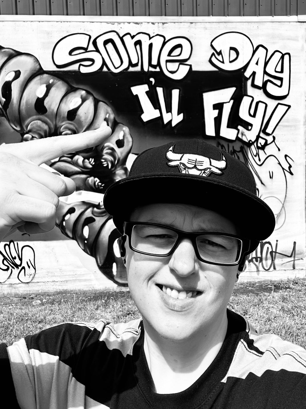 The founder of Spectrum Supports Tasmania in front of a street art mural reading 'Some Day I'll Fly'