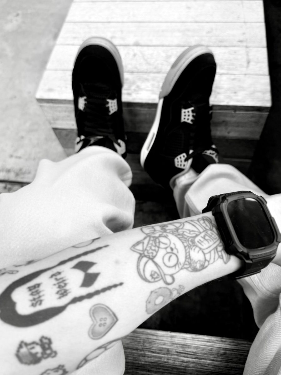 Tattooed arm resting on sneakers — a glimpse of the real person behind the work